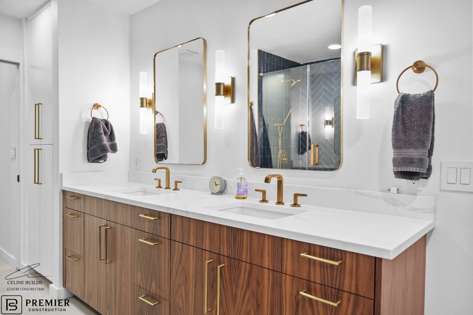 Bathroom after renovation - luxury walnut vanity with gold fixtures and modern sconces
